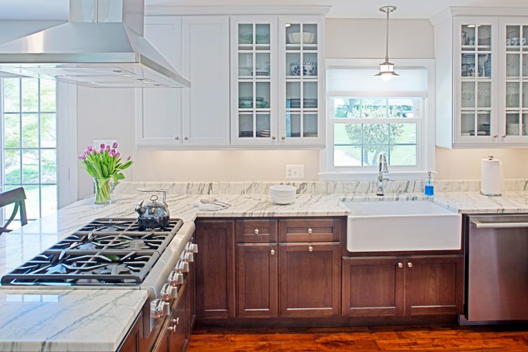 kitchen with wood floors dark wood lower cabinets white upper cabinets with glass doors peninsula and farmhouse sink