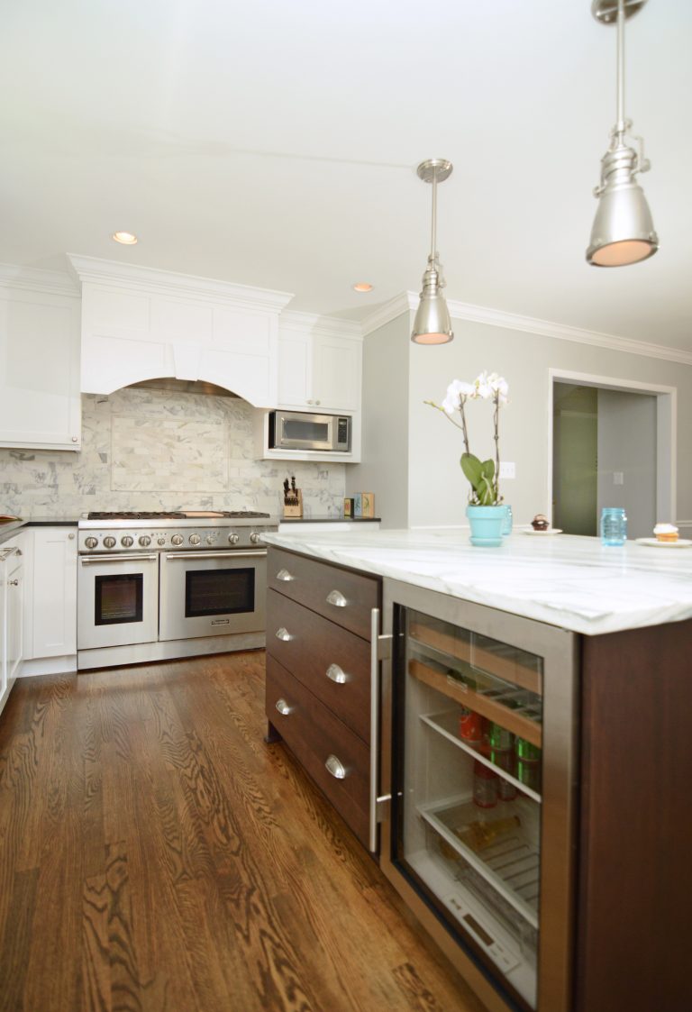 bright and open kitchen large range with hood pendant lighting hanging over dark wood island with beverage fridge