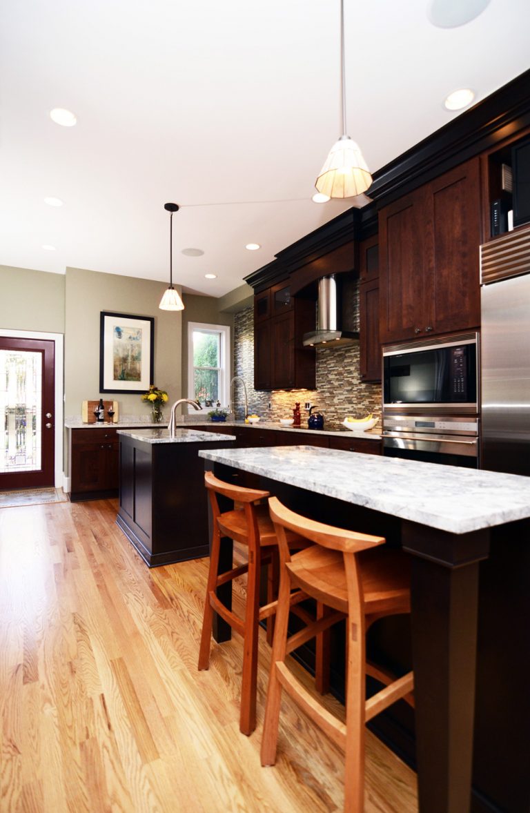 renovated kitchen dark cabinetry light wood floors double island