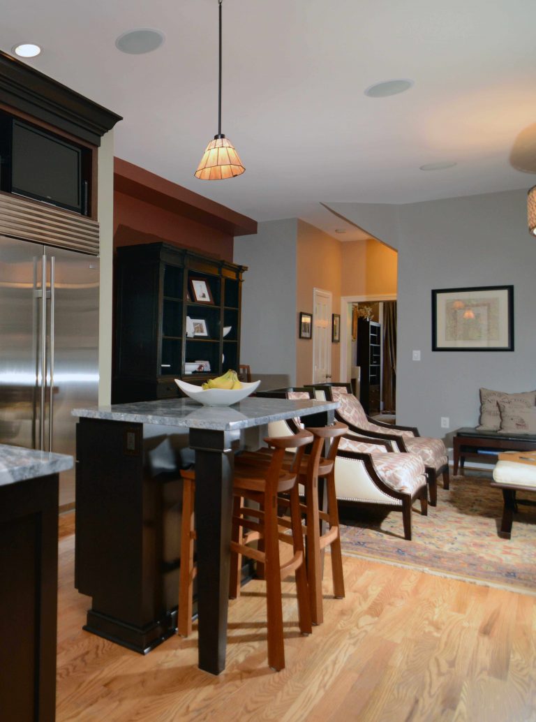 dc home renovated kitchen flows into living area pendant lighting over island stainless steel appliances soft blue walls and warm color tones