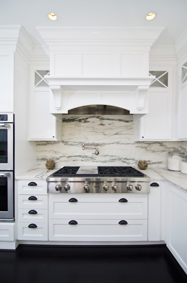 bright kitchen stove top wood paneled hood marble backsplash wall mounted potfiller