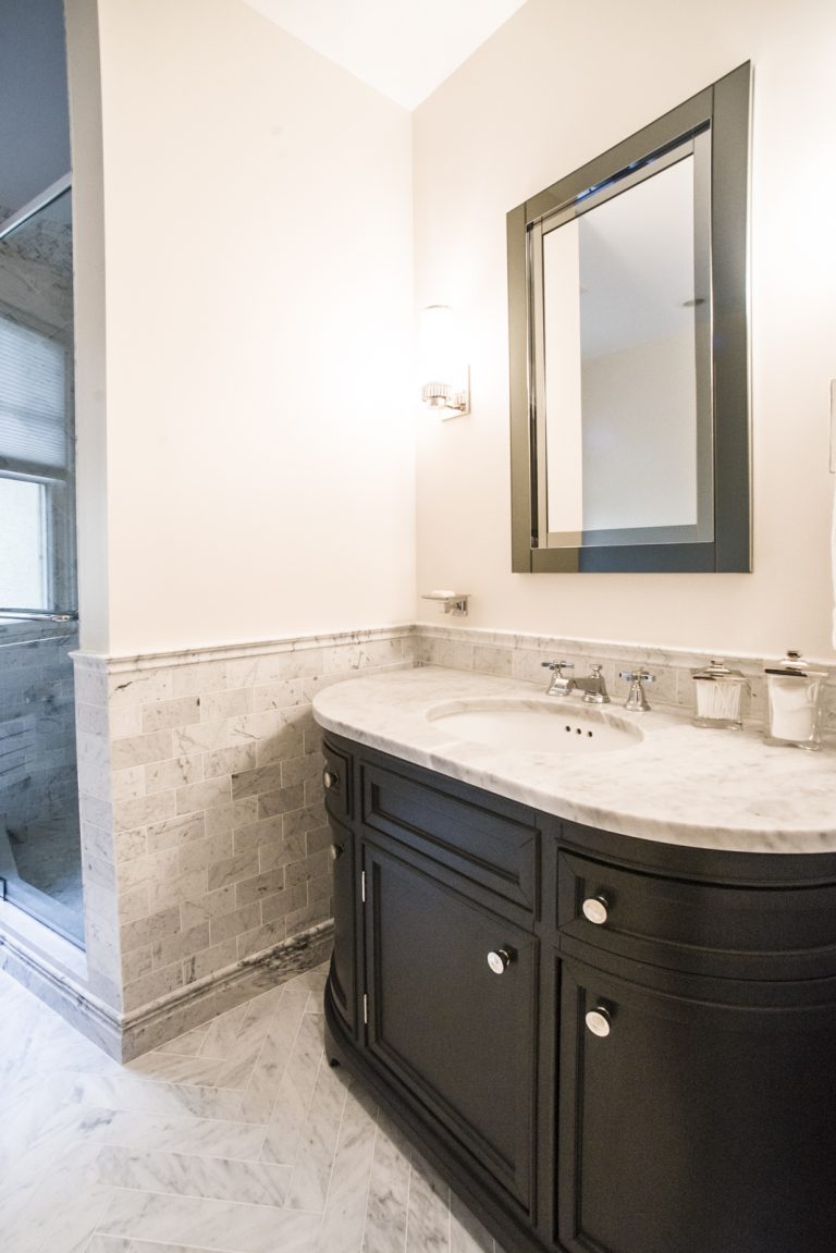 remodeled bathroom dark wood curved vanity light countertops and tile sconce lighting