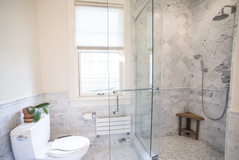 large shower stall with glass door and marble tiling