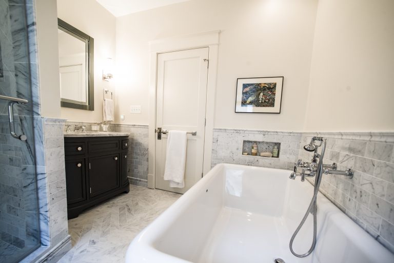 separate tub with hand shower marble wainscoting bright renovated bathroom