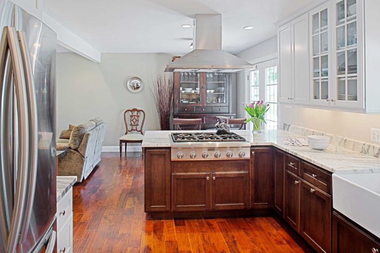 bright and open kitchen farmhouse sink gas range built into peninsula wood floors stainless steel appliances and range hood