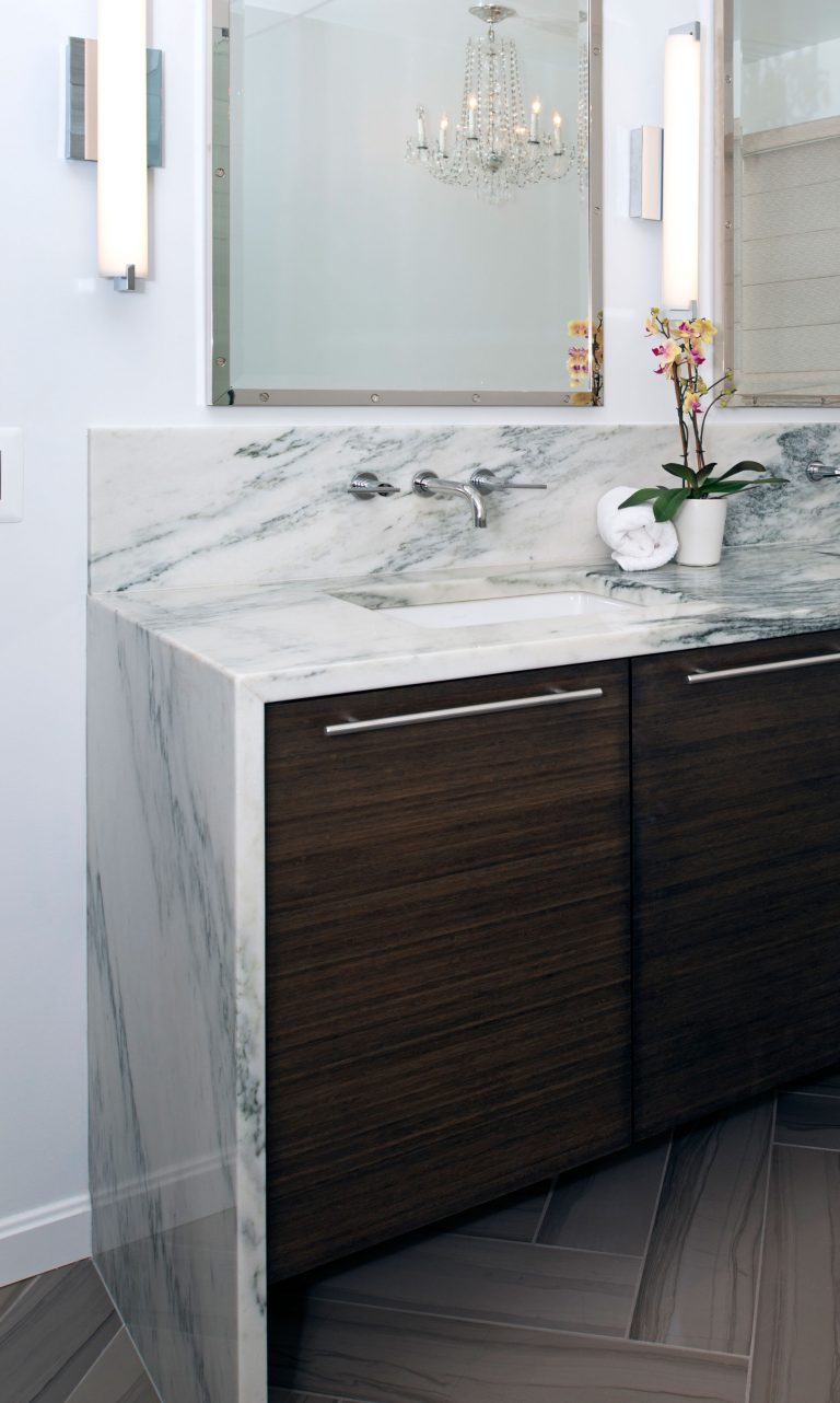 double sink dark wood vanity with waterfall edge marble countertops wall mount faucets and sconce lighting