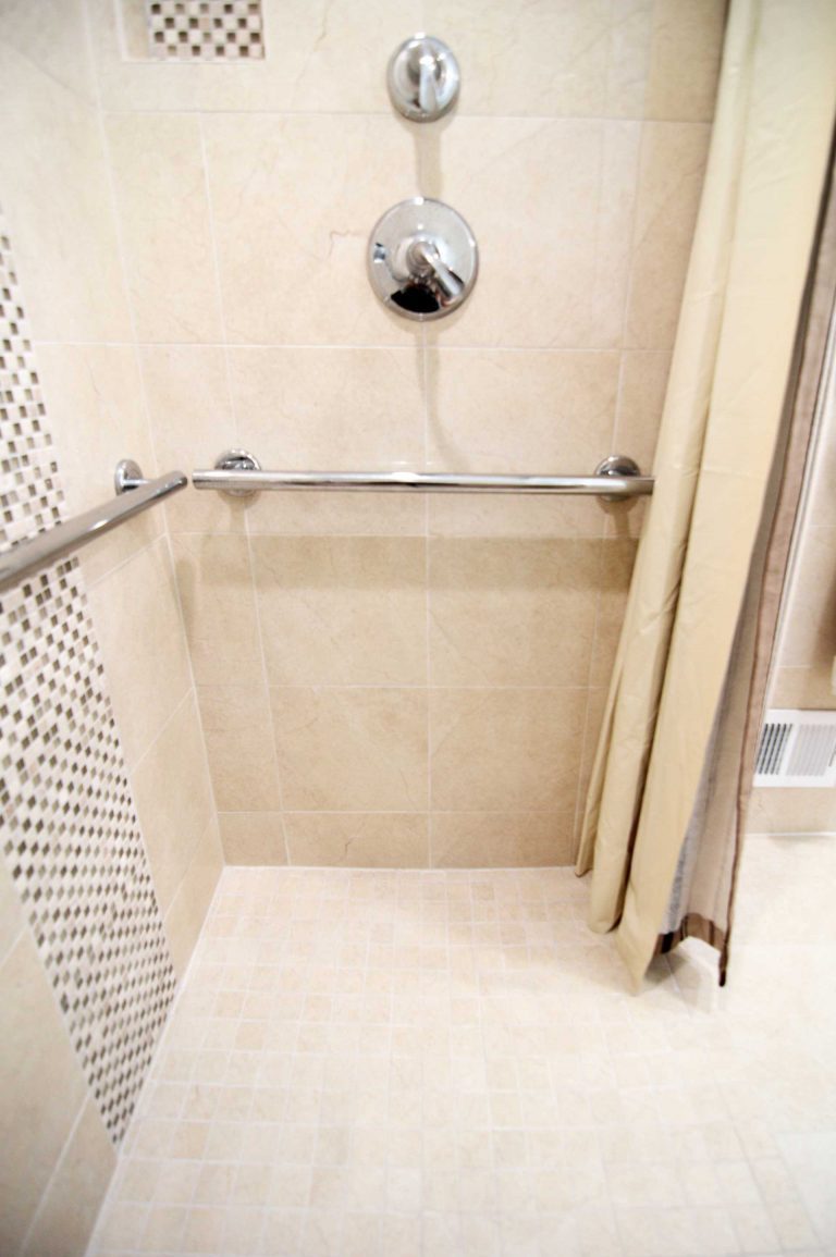accessible shower with grab bars built in storage nook and mosaic tile feature