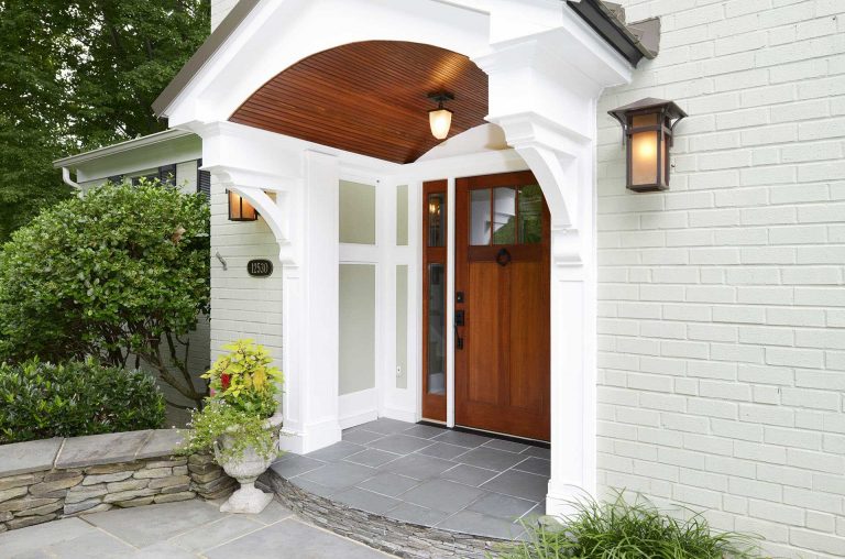 renovated entryway with covering wood door sconce and overhead outdoor lighting