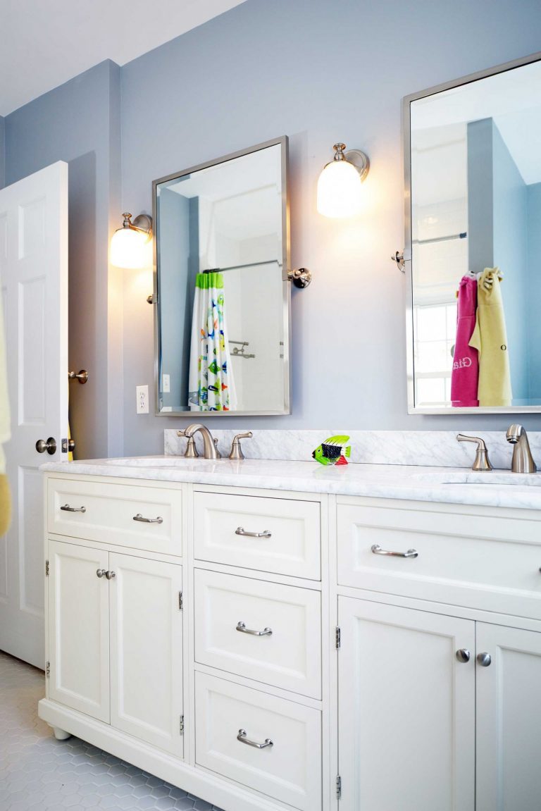 white cabinet vanity with double sinks and chrome hardware sconce lighting soft blue walls
