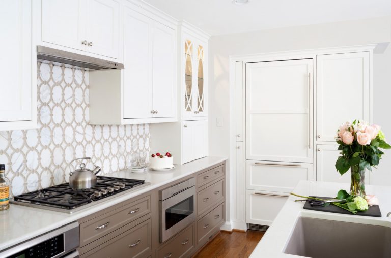 traditional kitchen neutral color palette gray toned lower cabinetry paneled refrigerator geometric tile backsplash gas stovetop range
