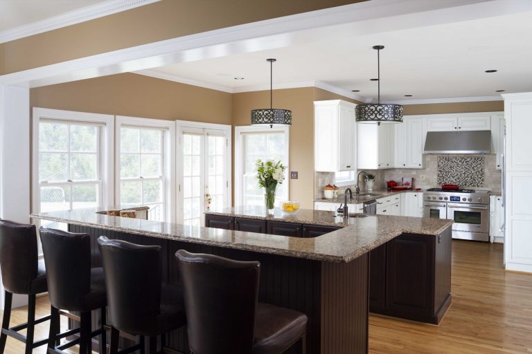 double islands and bar seating in kitchen mixed dark and white cabinetry warm neutral color palette large windows pendant lighting