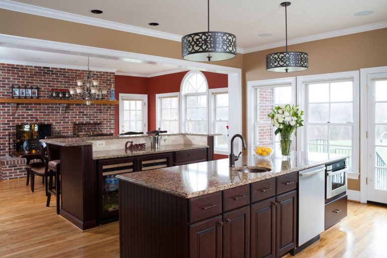 large traditional kitchen double islands flows into dining area exposed brick wall large glass door and windows warm neutral color tones