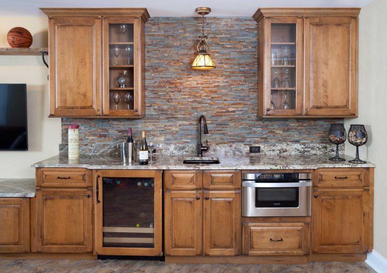 home sports bar medium stained cabinetry with glass door uppers stone backsplash beverage fridge mini sink pendant light