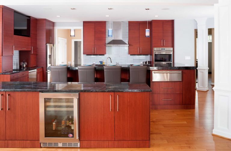 modern kitchen flows into living space cherry cabinetry bar seating at island stainless steel appliances and beverage refrigerator