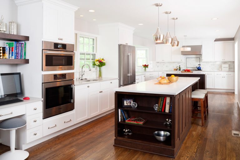 full shot of kitchen with island open storage on end white cabinetry wood floors stainless steel appliances pendant lighting