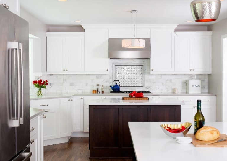 kitchen with white outer cabinetry and dark wood islands stainless tile backsplash with mosaic detail over range