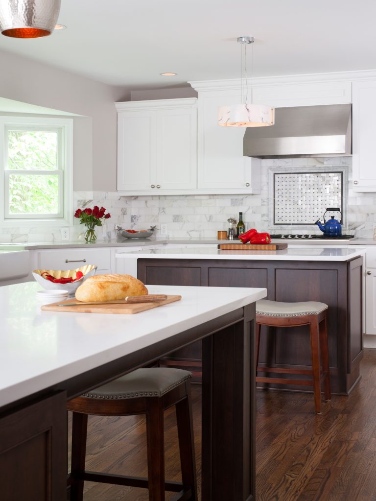 traditional style kitchen wood floors white cabinetry with dark cabinetry island with seating backsplash detail