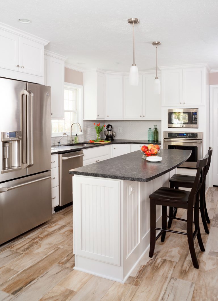 traditional kitchen natural wood floors white cabinetry black countertops pendant lighting over island