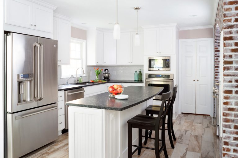 traditional kitchen natural wood floors white cabinetry black countertops pendant lighting over island