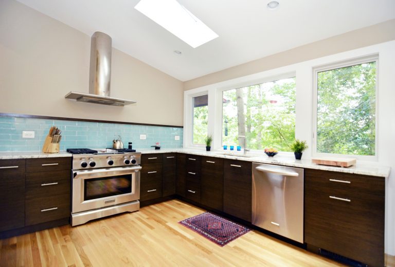 bright modern kitchen with skylights blue tile backsplash large window and mixed wood tones