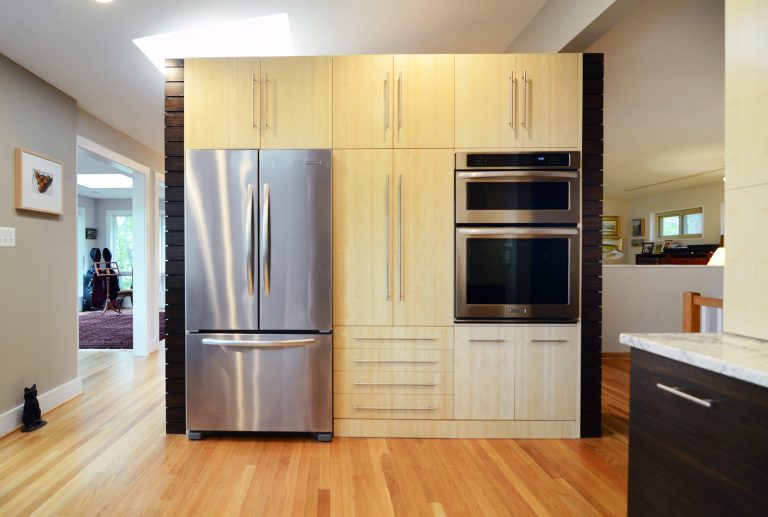 modern kitchen addition light wood cabinetry natural wood floors stainless steel appliances and wall oven