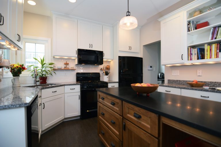 renovated kitchen white and dark cabinetry dark wood floors center island with seating black appliances