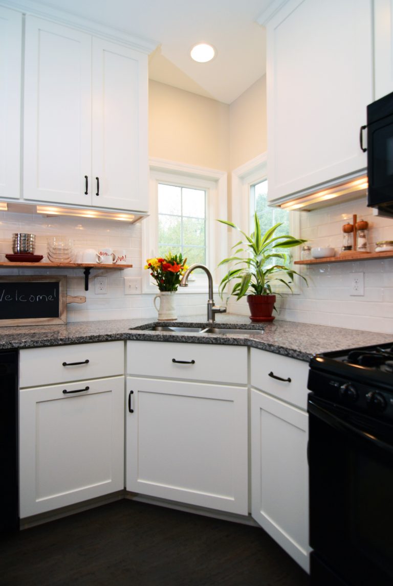 renovated kitchen with white cabinetry and dark wood floors black appliances