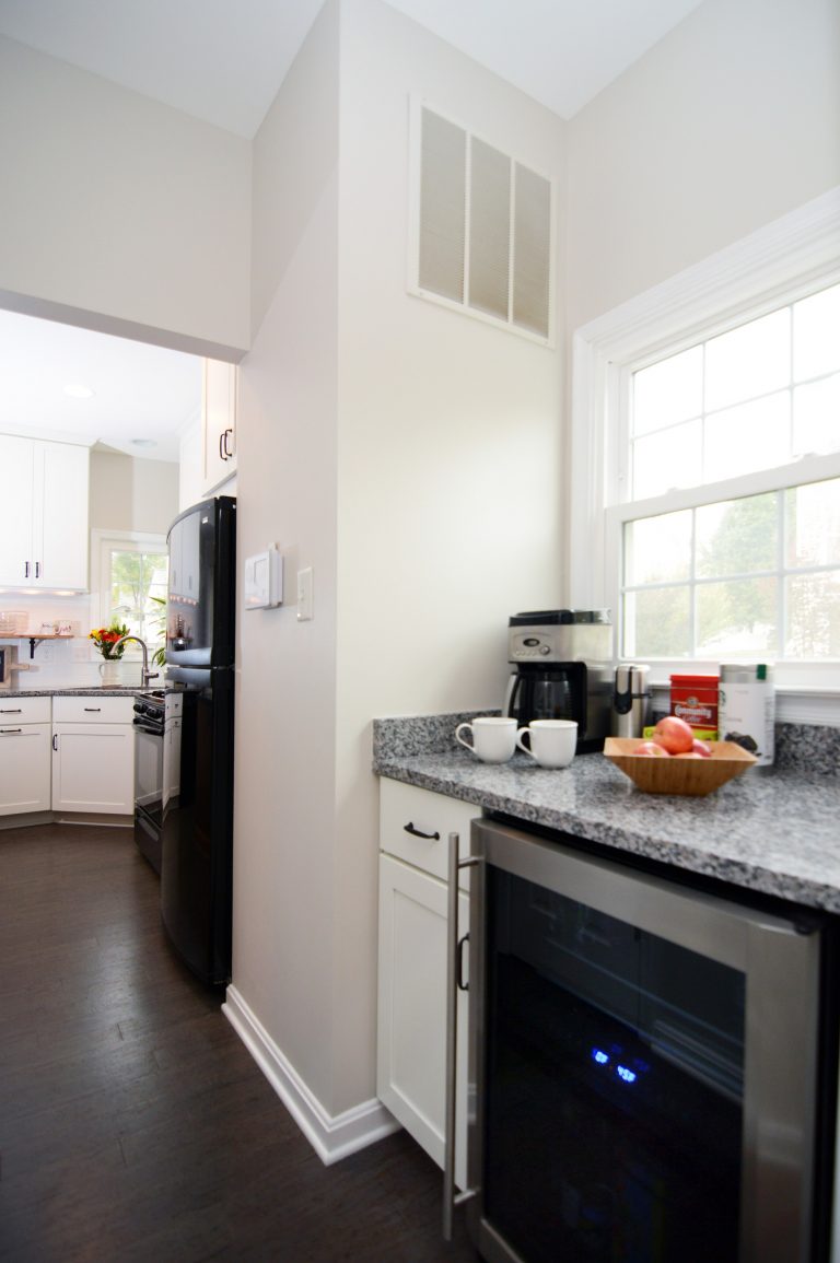 renovated kitchen white cabinetry dark wood floors stainless steel beverage refrigerator gray countertops