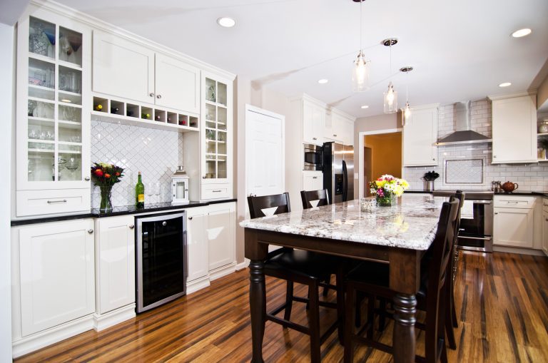 farmhouse style kitchen white cabinetry with dark wood island and bar area pendant lighting and recessed lighting