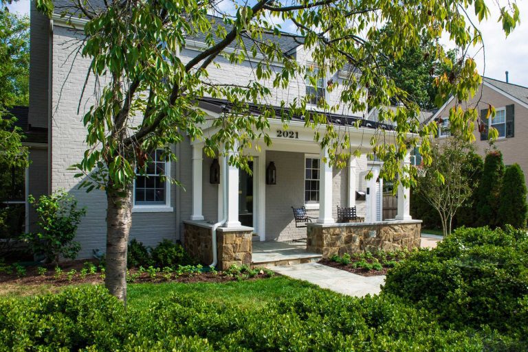 overview of front porch addition traditional farmhouse style stone and lush greenery