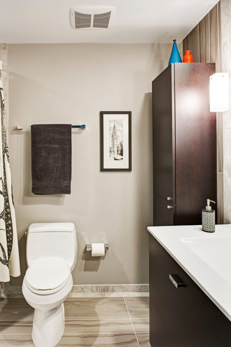modern bathroom remodel natural beige color palette dark wood cabinetry and vanity floor to ceiling storage