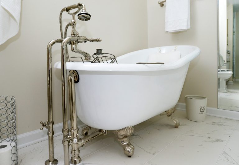 bright white bathroom with marble floors freestanding clawfoot tub with brass hardware