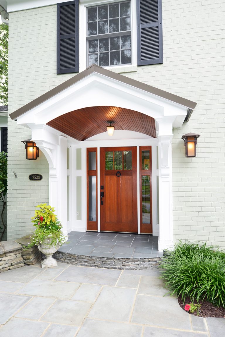 renovated entryway with covering wood door stone walk up sconce and overhead outdoor lighting
