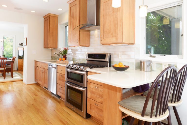 craftsman style kitchen natural stained wood cabinetry with peninsula and seating stainless steel appliances electric range and glass hood