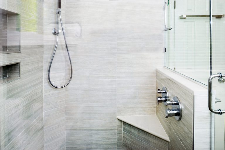 modern bathroom remodel shower stall with glass door built in bench and storage nook gray tiling