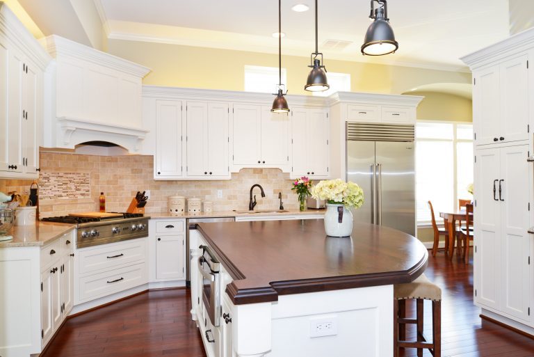 center island white cabinets and dark wood colored countertop flows into dining room windows above upper cabinets