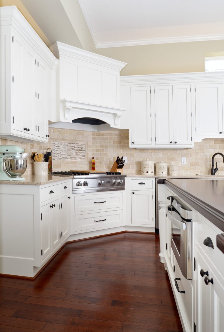 traditional kitchen dark wood floors white cabinetry gas range angled in corner with wood paneled hood vent