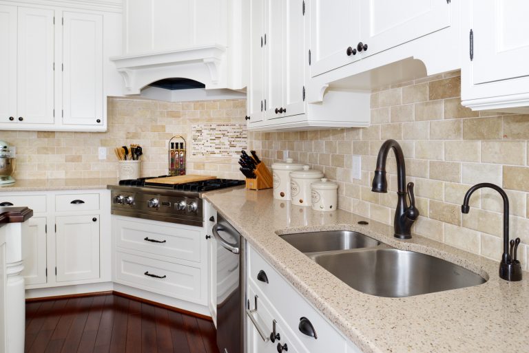 traditional kitchen dark wood floors white cabinets beige countertops and tile backsplash