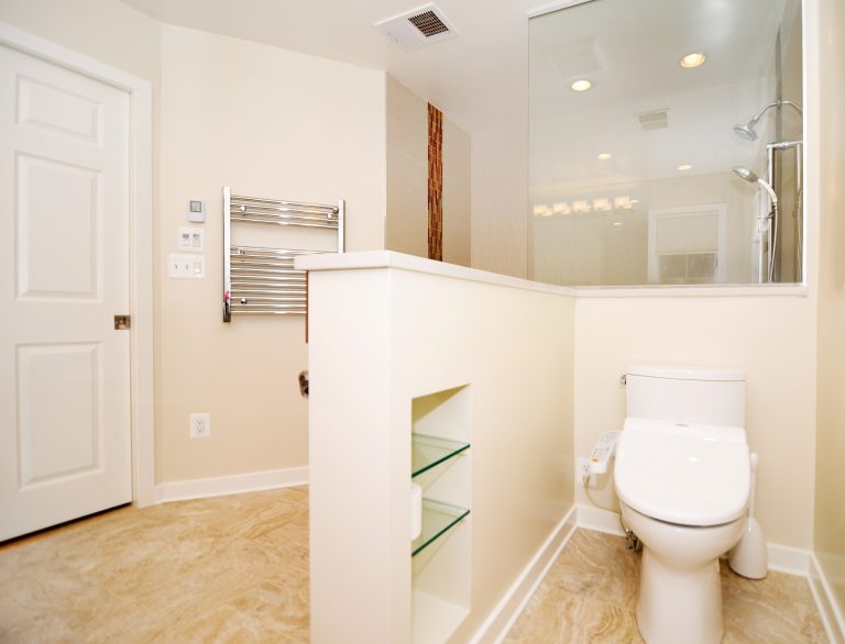 large neutral color bathroom with glass shower stall and built in storage