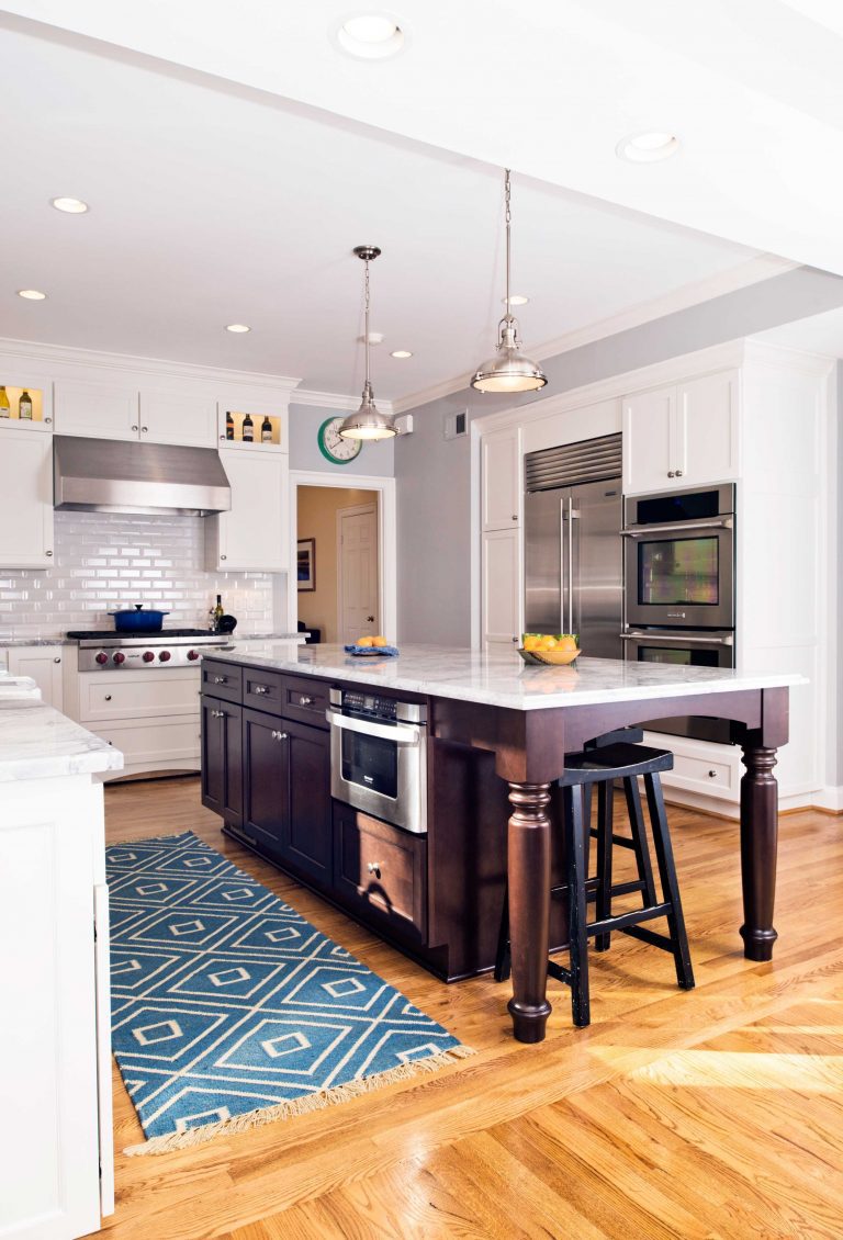 bright white kitchen with wood floors and dark wood island stainless steel appliances subway tile backsplash pendant and recessed lighting