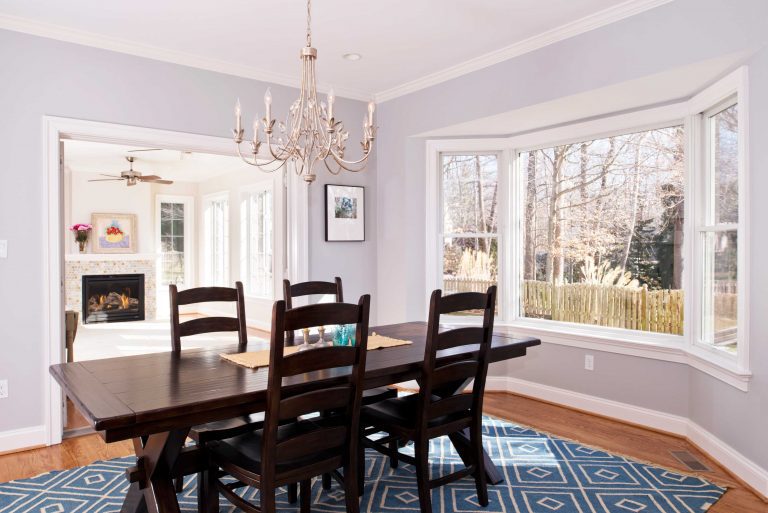 updated dining area off of living room soft purple walls chandelier bay window crown molding