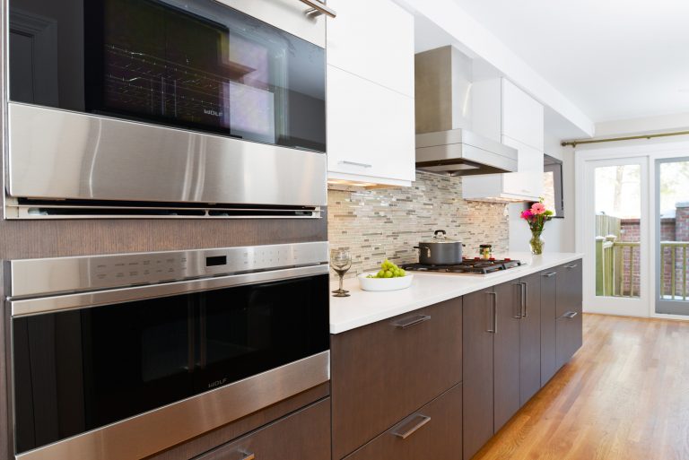 modern kitchen dark cabinetry white upper cabinets stainless steel appliances double wall oven