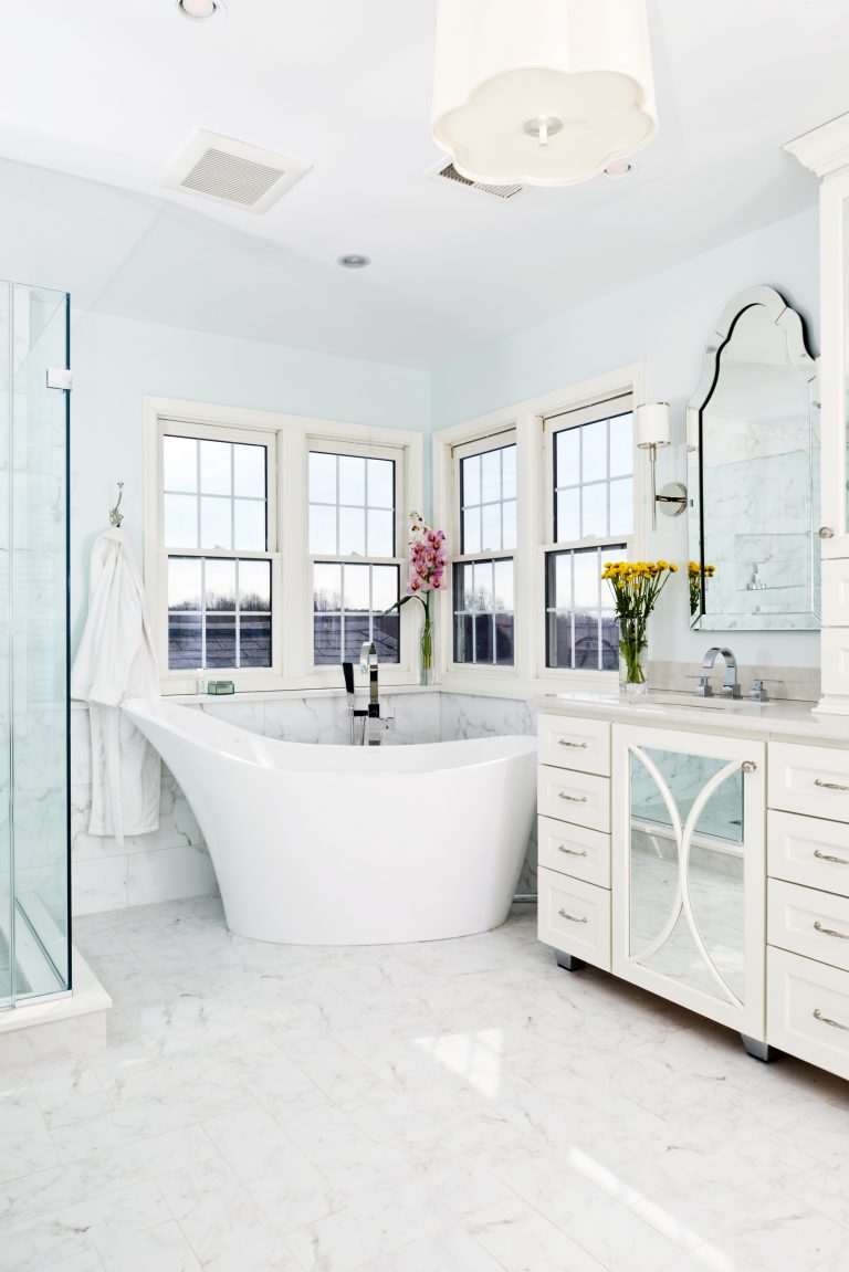 bright beachy bathroom light blue walls freestanding tub large windows mirror paneled cabinetry