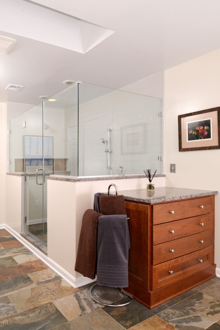 renovated bathroom with skylight large shower stall with glass doors and built in storage nook neutral color palette