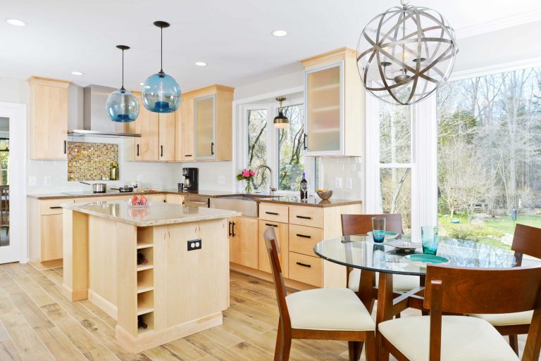 modern eat-in kitchen with center island light wood cabinetry large windows and pendant lighting