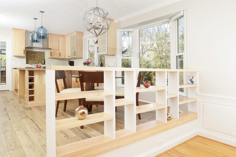 light wood built-in open shelving divides kitchen from sunken living area