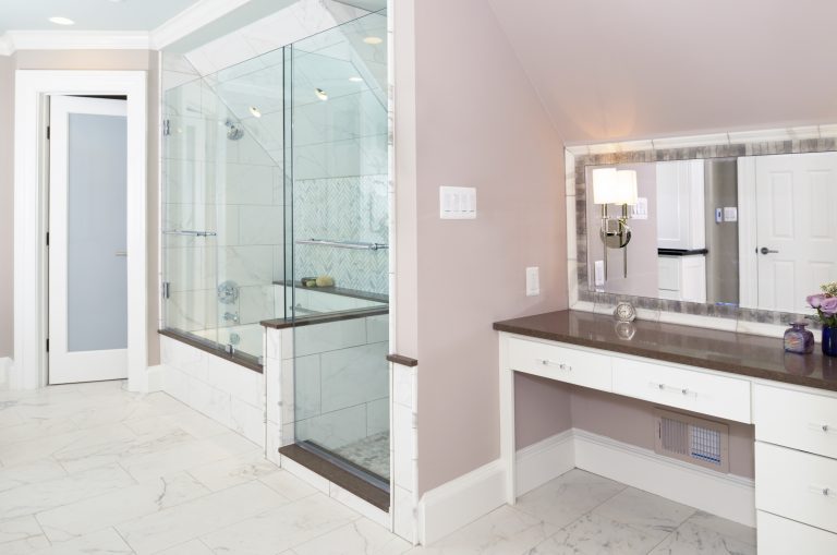 modern bathroom design with soft pink color palette separate tub and shower stall built in vanity with brown countertops