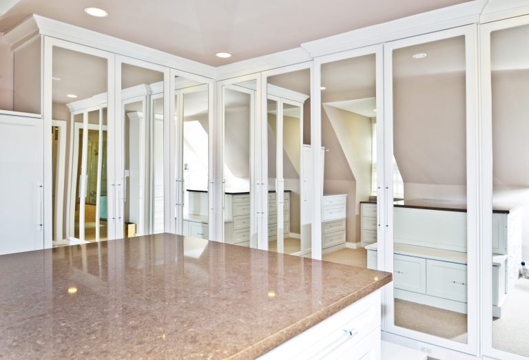 renovated master closet neutral pink color tones mirrored doors and island