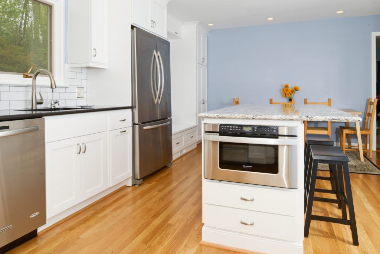 bright renovated kitchen wood floors white cabinetry stainless steel appliances