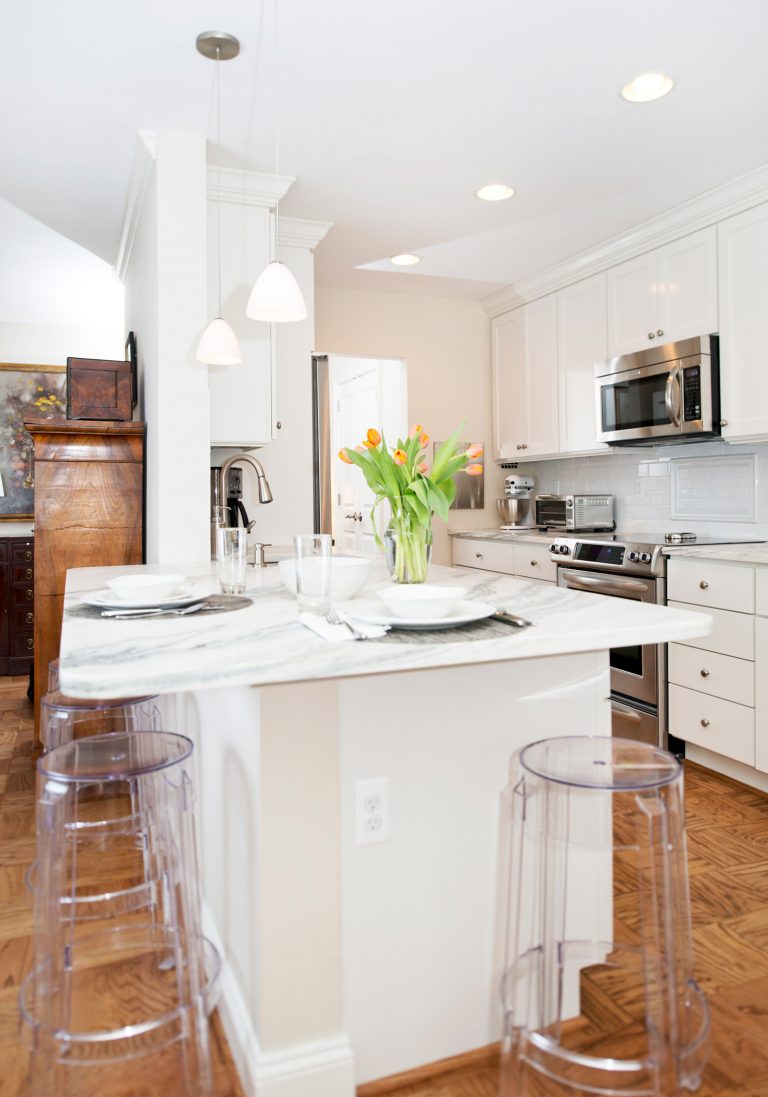 traditional kitchen white cabinetry light countertops peninsula with seating pendant lighting and parquet floors